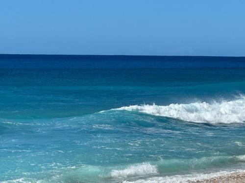 a wave in the ocean on a beach at NEW HOME in Private Community with Ocean/Mountain Views. 5 Min. Drive to Beach in Waianae