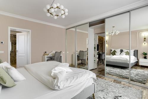 - une chambre blanche avec un lit et un miroir dans l'établissement Sika Royal Central Apartment, à Arad