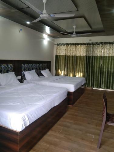 1 dormitorio con 2 camas y ventana en Badrinath B V by prithvi yatra hotels, en Badrīnāth