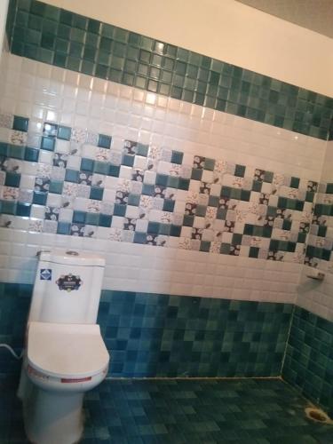 a bathroom with a toilet and a tiled wall at Badrinath B V by prithvi yatra hotels in Badrīnāth