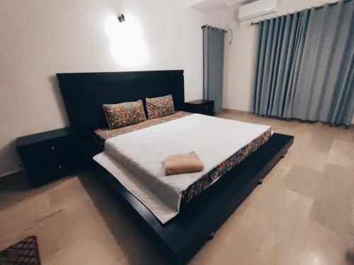a bedroom with a large bed with a black headboard at Daily BASIS 3-BEDROOMS FAMILY APARTMENT in Islamabad