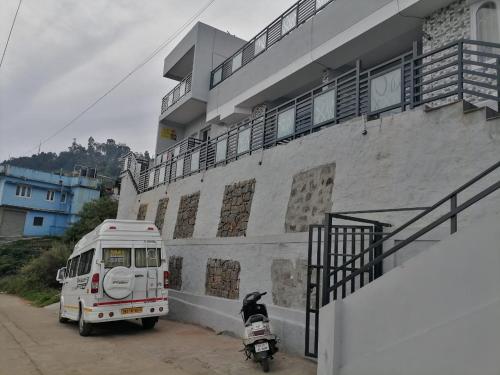 biały van zaparkowany obok budynku z motocyklem w obiekcie Summer Dreams Cottage Kodaikanal w mieście Kodaikānāl