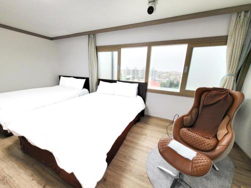 a hotel room with two beds and a chair at Top Island Hotel in Jeju