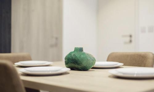 una mesa con platos y un jarrón verde. en Luxurious loft space Available en Accra