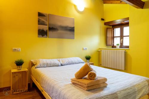 Dormitorio amarillo con cama con toalla en La casita de la Senda, 