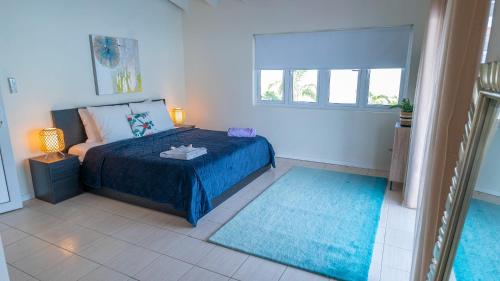 a bedroom with a bed with blue sheets and a window at Sunny Eagle Beach Villa - 3 min. from beach in Palm-Eagle Beach