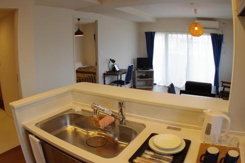 a kitchen with a sink and a living room at 笠岡　潮待ちHOTEL 