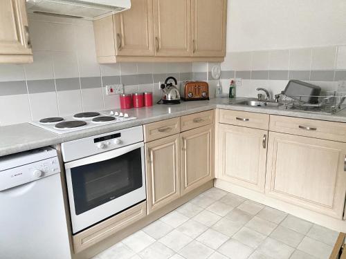 a kitchen with wooden cabinets and a white stove top oven at Ground floor Central 1 bed with parking in Aberdeen