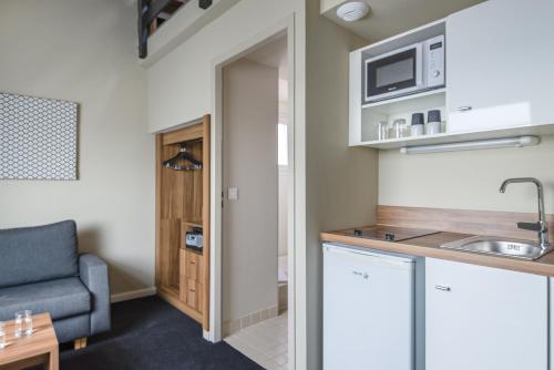 a kitchen with a sink and a couch in a room at Best Western Hotel Atrium Valence in Valence