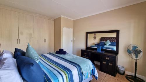 ein Schlafzimmer mit einem Bett mit blauen Kissen und einem Spiegel in der Unterkunft Sunrise Serenity Guest House in Lydenburg