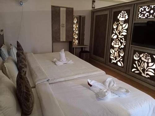 a bedroom with two beds with white towels on them at Sri Gnana Vedha Beach Residency in Velānganni