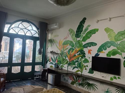 een woonkamer met een muurschildering van planten op de muur bij Nemohousehomestay in Hanoi