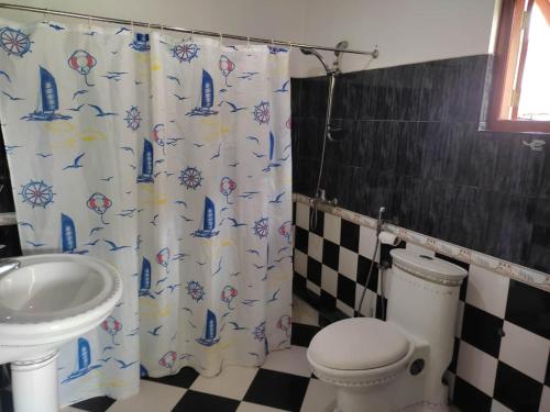 a bathroom with a toilet and a sink and a shower curtain at Utopia Hikka in Hikkaduwa