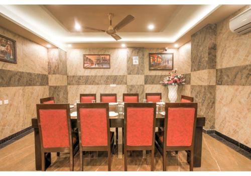 a dining room with a table and red chairs at Kusum House in Greater Noida