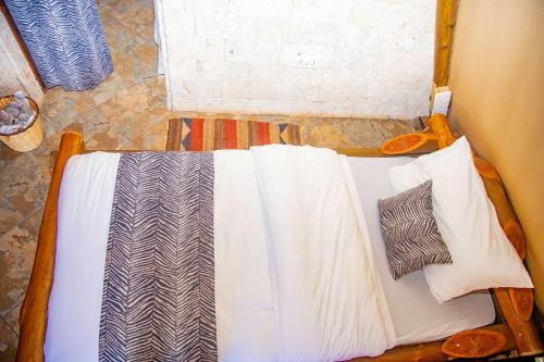 a bed with two pillows on it in a room at Boma Simba Safari Lodge in Voi