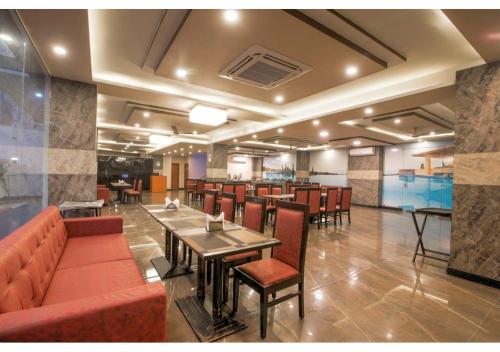 a restaurant with tables and chairs and a bar at Kusum House in Greater Noida