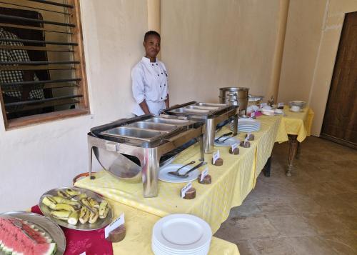 Ein Mann steht vor einem Tisch mit Essen. in der Unterkunft Boma Simba Safari Lodge in Voi