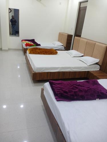 a group of three beds in a room at Hotel soham palace in Ujjain