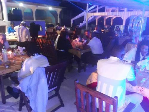 un grupo de personas sentadas en mesas en un restaurante en HOTEL DU BAR DE LA MER CAP SKIRRiNG en Kabrousse