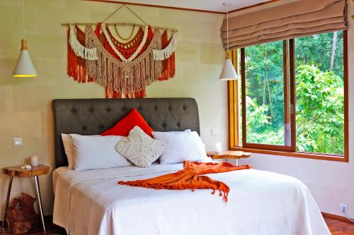 a bedroom with a white bed with a red blanket on it at Villa Merdu Ubud in Ubud