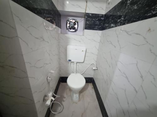 a bathroom with a white toilet and marble walls at Krishna Homestay in Faizābād