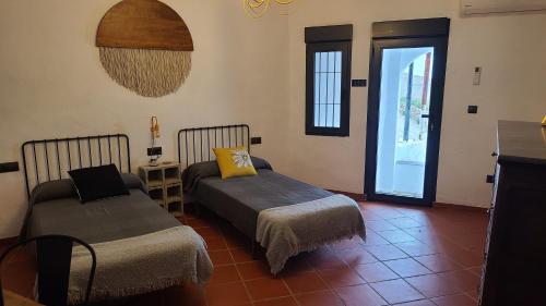 Habitación con 2 camas, mesa y ventana en CASA CUEVA A-TIPICA, en Pegalajar