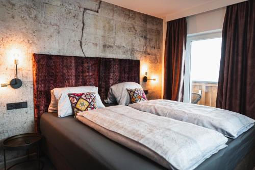 a bedroom with a large bed with a concrete wall at PHILSON Apartments in Saalbach Hinterglemm