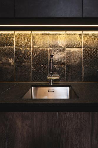 a stainless steel sink in a kitchen with gold tiles at PHILSON Apartments in Saalbach Hinterglemm