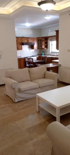 a living room with two white couches and a kitchen at Al- Kalouti Real Estate in Amman
