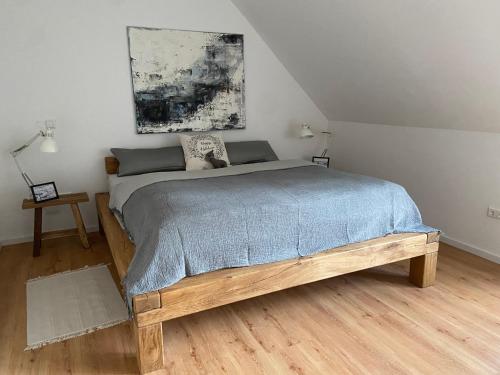a bedroom with a wooden bed with a painting on the wall at Harzpur Lodge - Pure Entspannung in purer Natur in Hahnenklee-Bockswiese