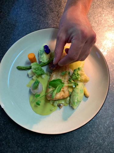 a person holding a plate of food on a table at Logis Hotel Du Midi in La Roche-en-Ardenne