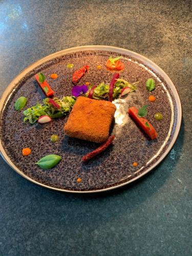a plate with a sandwich and vegetables on it at Logis Hotel Du Midi in La Roche-en-Ardenne