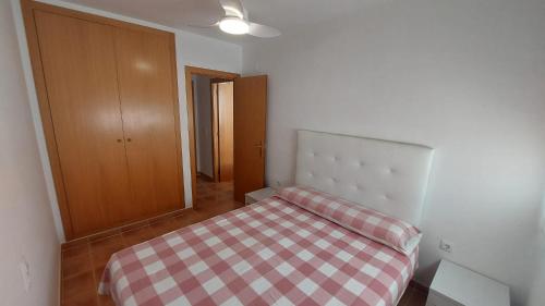 a small bedroom with a bed with a checkered blanket at Ático dúplex con vistas in Canet de Berenguer