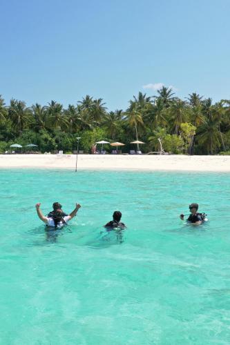 three people swimming in the water in the ocean at Manta Sea View Himandhoo in Himandhoo 
