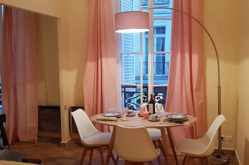 une table à manger avec des chaises blanches et une fenêtre dans l'établissement Appartement dans le Marais 3 chambres, à Paris