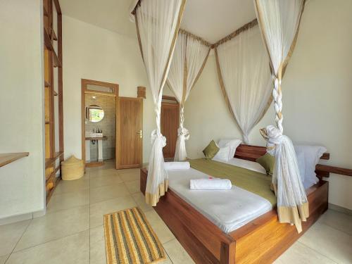 a bedroom with a bed with a canopy at Villa Cas' Ylang Nosy Be in Nosy Be