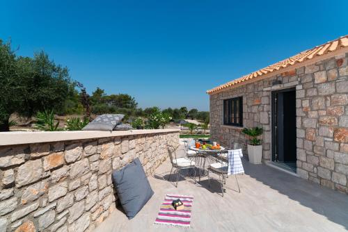 a stone wall with a table and chairs on a patio at AGROTOPIA Guesthouses in Theologos