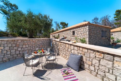 a patio with a stone wall and a table and chairs at AGROTOPIA Guesthouses in Theologos