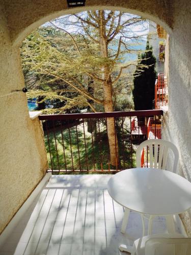 d'une table et d'une chaise blanches sur un balcon avec vue. dans l'établissement Le Clos des Oliviers idéal curiste et travailleurs Cadarache, à Gréoux-les-Bains