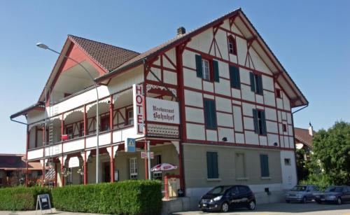 a large white and red building with cars parked in front at Hotel Restaurant Bahnhof in Schüpfen