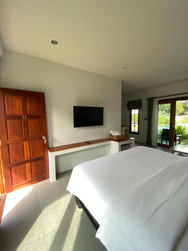 a bedroom with a white bed and a flat screen tv at Baan Yaimai Boutique Samui in Bophut