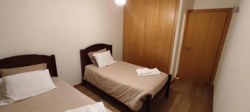 Habitación pequeña con 2 camas y puerta de madera. en Apartamento Quitéria - Funchal, en Funchal
