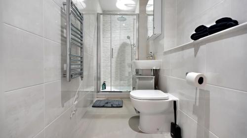 a white bathroom with a toilet and a window at Modern and Spacious Penthouse Apartment in Putney with Free Parking in London