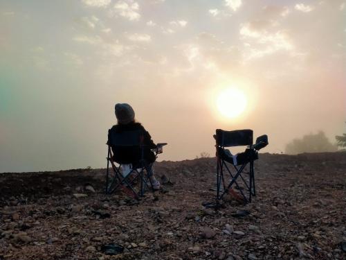 two people sitting in folding chairs watching the sunset at Doi Sang Farm Stay - ดอยซางฟาร์มสเตย์ in Ban Huai Kom