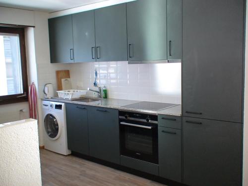 a kitchen with blue cabinets and a washing machine at Relax aux Paccots : été comme hiver in Les Paccots