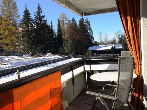 a table and a chair on a balcony with a window at Relax aux Paccots : été comme hiver in Les Paccots