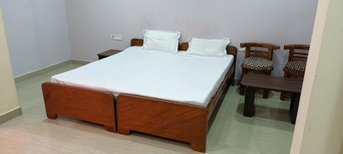 - un lit avec 2 oreillers dans une chambre avec des chaises dans l'établissement HOTEL SANJIBAN, à Māldah