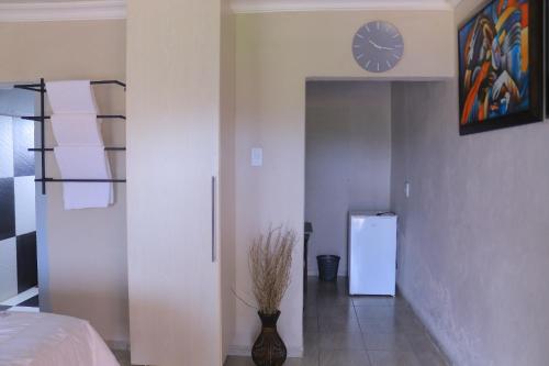 a bedroom with a clock on the wall and a refrigerator at Lis ville guest house in Phalaborwa