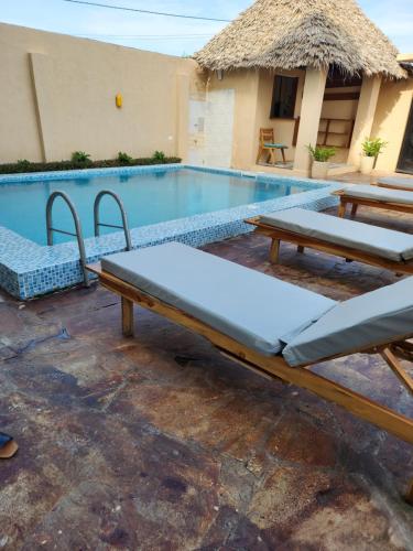 a swimming pool with two picnic tables next to a building at Cappadocia Hotel in Nungwi