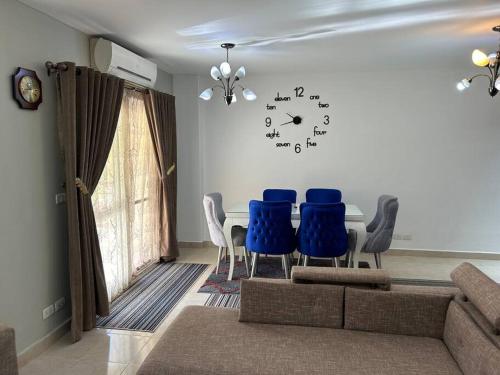 a living room with a table and chairs and a clock on the wall at Luxury Inn 3BR Amazing Garden view in Madinaty B1 in Madinaty